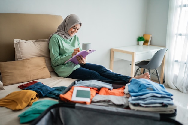 Hidżab kobieta siedzi na łóżku, patrząc na książkę