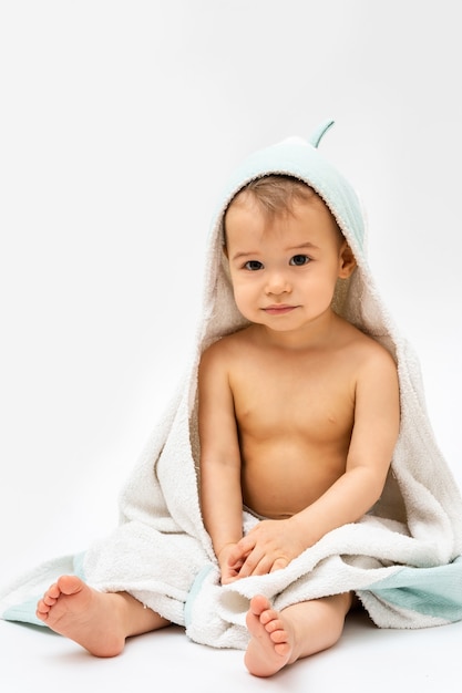 Higiena i pielęgnacja dziecka. Śliczny chłopczyk zawinięty w ręcznik z kapturem po kąpieli.