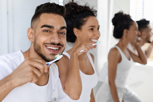 Higiena jamy ustnej szczęśliwy młody arabski mężczyzna i kobieta szczotkują zęby w łazience