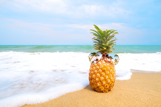 Hipster ananas z okularami przeciwsłonecznymi na piaszczystej plaży