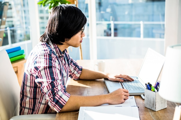 Hipster biznesmen pisania podczas korzystania z laptopa w biurze