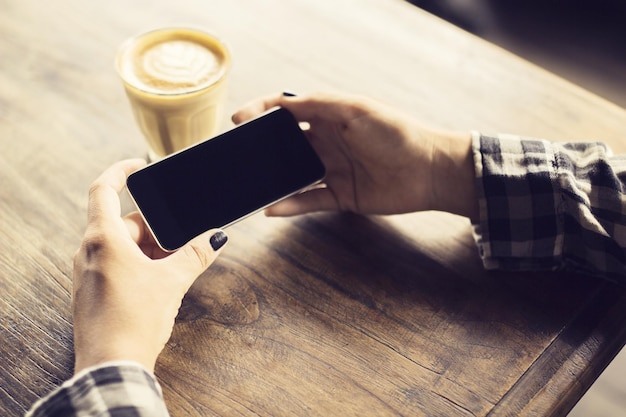 Hipster dziewczyna ręce z telefonem komórkowym i filiżanką kawy
