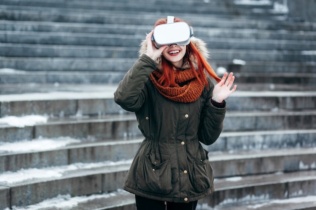 Hipster młoda dziewczyna gra w mobilną grę wirtualnej rzeczywistości na smartfonie podłączonym do nowoczesnych okularów VR na zewnątrz