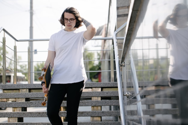 Hipster przystojny model męski ubrany w białą pustą koszulkę z miejscem na logo lub projekt w swobodnym miejskim stylu