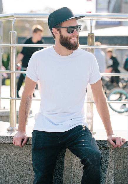 Hipster przystojny model męski z brodą w białej pustej koszulce z miejscem na Twoje logo lub projekt w swobodnym miejskim stylu