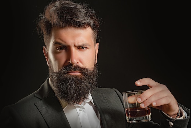 Hipster z brodą i wąsami w garniturze pije alkohol po dniu pracy stara tradycyjna whisky dri