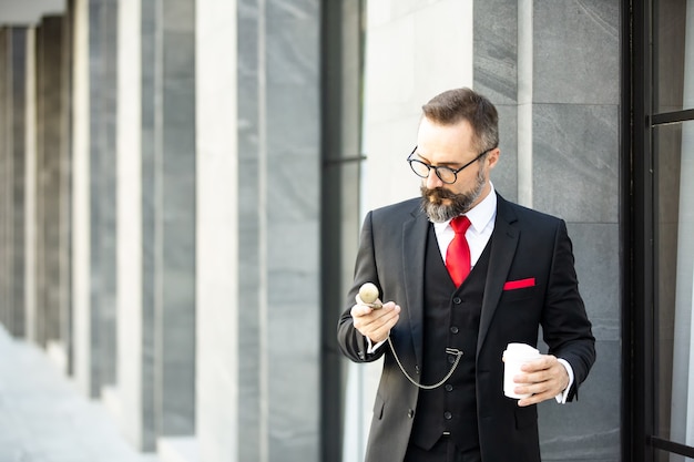 hipsterski biznesmen na czarnym garniturze stojący przed kawiarnią