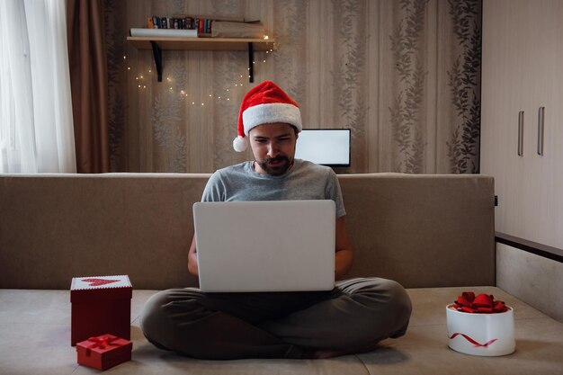 Hipsterski mężczyzna z czerwoną filiżanką siedzący w domu na Boże Narodzenie