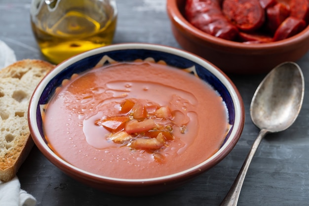 Zdjęcie hiszpańska zupa gazpacho w misce z chlebem i oliwą z oliwek na ceramicznym tle