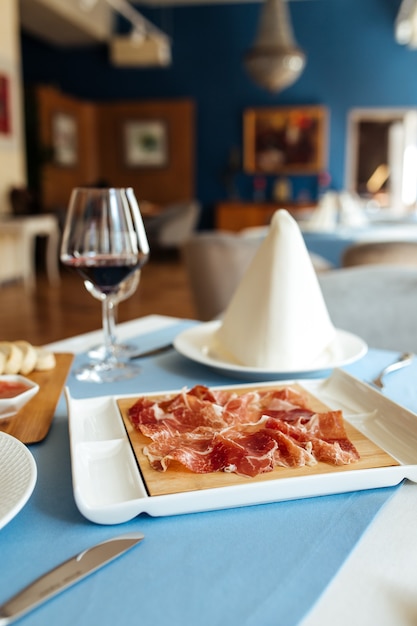 Hiszpański jamon wieprzowy w plasterkach z czerwonym winem na stole w restauracji