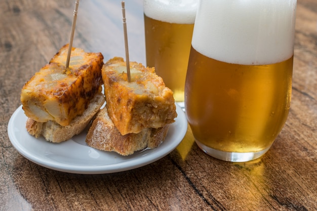 Hiszpański omlet i dwie szklanki piwa na drewnianym stole