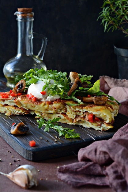 Hiszpański tradycyjny omlet tortilla z kremowymi świeżymi ziemniakami, grzybami i świeżą rukolą