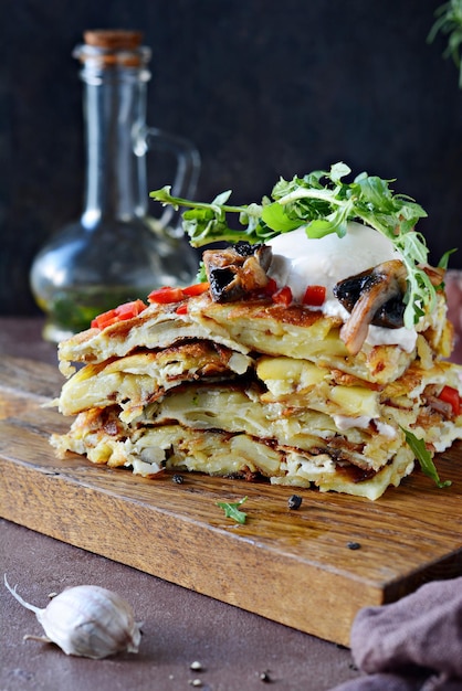 Hiszpański tradycyjny omlet tortilla z kremowymi świeżymi ziemniakami, grzybami i świeżą rukolą