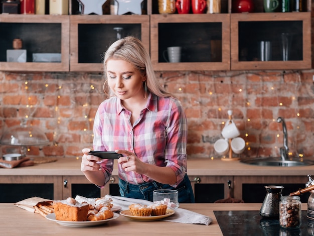 Hobby blogowania żywności. Słodki asortyment domowych wypieków. Kobieta z smartphone strzelanie świeżych ciast i ciastek.