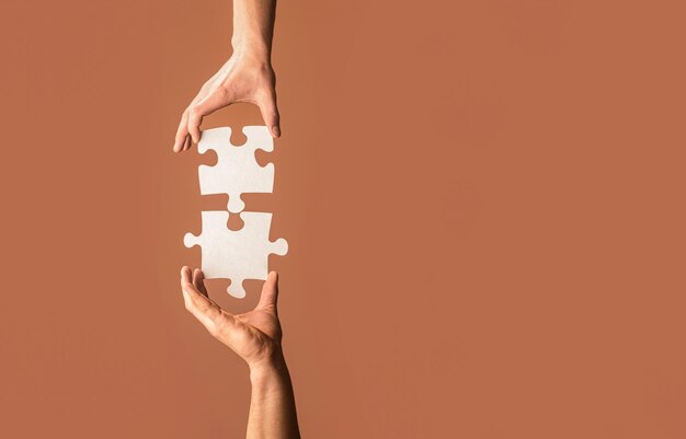 Holding puzzle Rozwiązania biznesowe sukces i koncepcja strategii Dwie ręce próbują połączyć para kawałek układanki na szarym tle Koncepcja pracy zespołowej Zbliżenie ręka łączenia układanki
