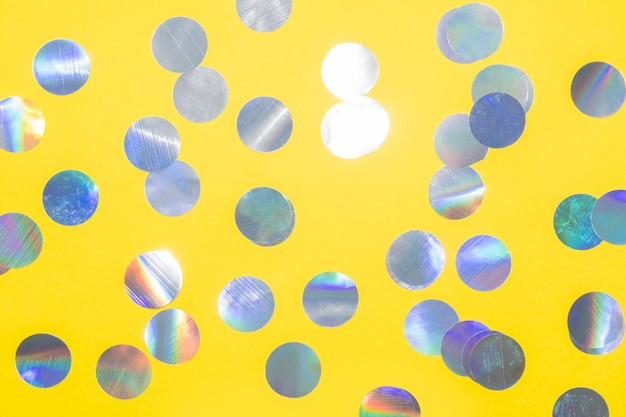 Holograficzny okrągły wzór konfetti na żółtym tle na świąteczne przyjęcie