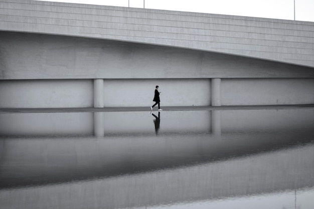 Zdjęcie hombre caminando con fondo blanco y negro simetrico y reflejo