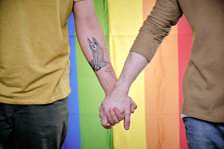Zdjęcie homoseksualiści trzymający się za ręce, gdy stoją przed tęczową flagą dumy