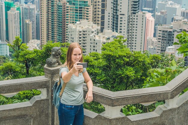 Hongkong victoria peak kobieta robi zdjęcie selfie stick ze smartfonem, ciesząc się widokiem