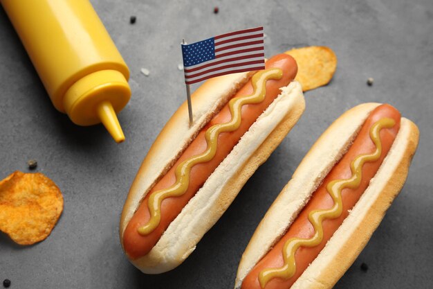 Hot dogi z musztardą i małą flagą usa na szarym tle