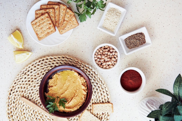 Hummus z pełnoziarnistymi ciasteczkami przystawka Domowa pasta wegetariańska z natką pietruszki plasterkami cytryny Papryka rzymska nasiona ciecierzyca składniki sezamu Widok z góry Jedzenie