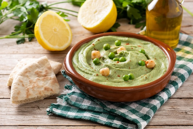 Hummus z zielonego groszku i chleb pita na drewnianym stole