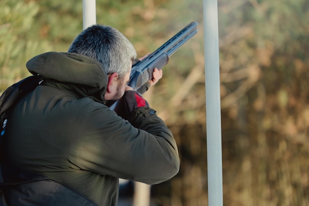 Hunter w kamuflażu z karabinem w zimowym lesie. Koncepcja polowania. Mężczyzna zabezpiecza rezerwat w śnieżny dzień. Łowca celuje z pistoletu w śnieżnym lesie