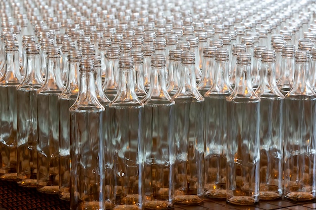 Huty szkła Przemysł szklarski Wiele szklanych butelek na fabrycznym przenośniku