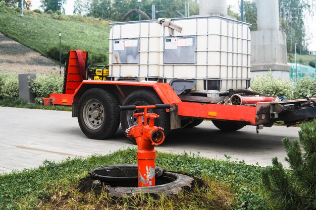 Zdjęcie hydrant przeciwpożarowy na tle przyczepy w zbiornikach wody do nawadniania roślin