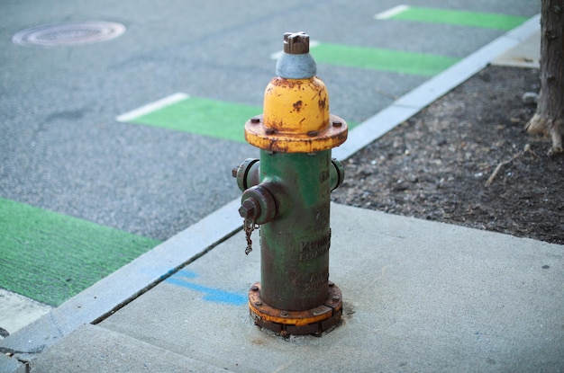 Hydrant przeciwpożarowy stoi na chodniku obok krawężnika.