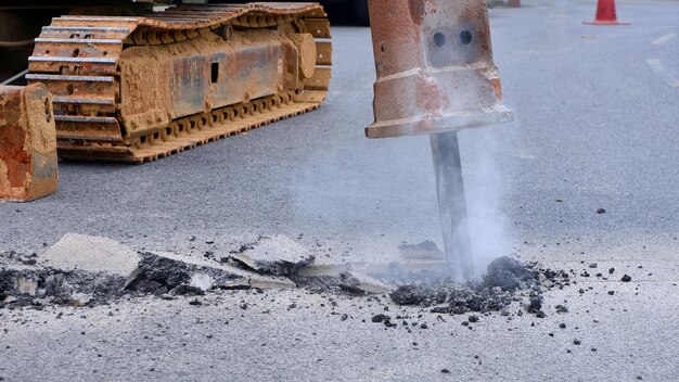 Hydrauliczny Młot Kruszący Koparki łamie Asfaltową Drogę W Celu Zainstalowania Systemu Rurociągów Wodnych