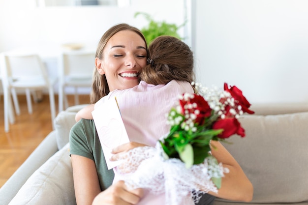 I love my you mom Atrakcyjna młoda kobieta z małą uroczą dziewczynką spędzają razem czas w domu dziękując za ręcznie wykonaną kartkę z symbolem miłości i kwiatami Szczęśliwa koncepcja rodziny Dzień matki