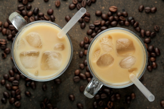 Ice latte lub mrożona kawa z mlekiem i kostkami lodu w szklanej zlewce na ciemnym tle. orzeźwiający napój. letni napój. widok z góry