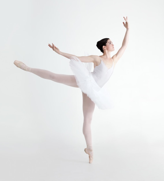 Idealna arabeska Elegancka młoda baletnica tańcząca en pointe na białym tle