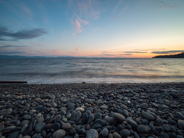 Zdjęcie idealna gładka kamienista plaża o zachodzie słońca na wyspie vancouver, kolumbia brytyjska, kanada.