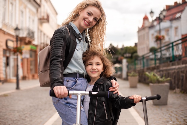 Identyczna mama i córka ze skuterami w mieście