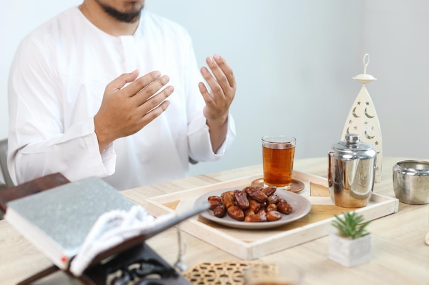 Iftar z ręką muzułmanina modlącego się do Allaha Dates owoc z szklanką gorącej herbaty na stole