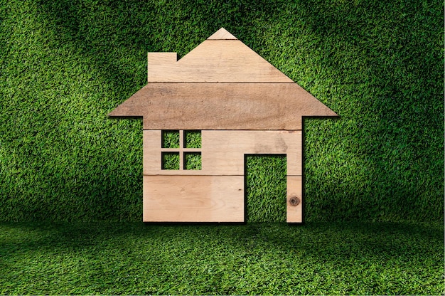 Ikona domu z drewnianej tekstury na tle trawy