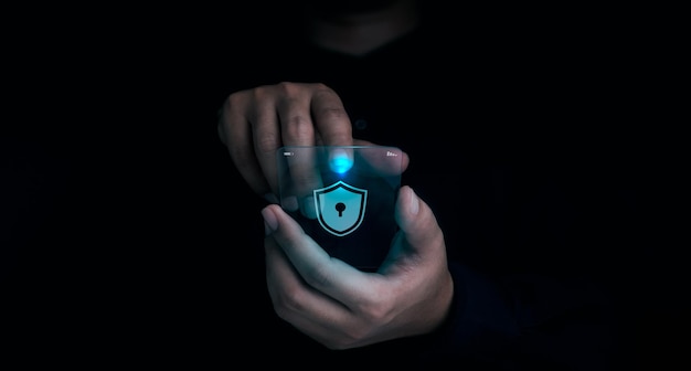 Zdjęcie ikony przycisku blokady tarczy pojawiły się, gdy palec mężczyzny dotyka przyszłego przezroczystego szkła inteligentny telefon komórkowy na ciemnym tle cyberbezpieczeństwo ochrona danych biznes prywatność koncepcja technologii
