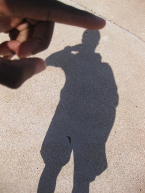 Zdjęcie iluzja optyczna człowieka dotykającego cienia na ulicy