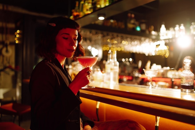 Impreza koktajlowa. koktajl w rękach kobiety. Młoda kobieta pije koktajle w barze.