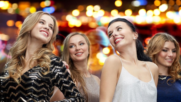 impreza, wakacje, życie nocne i koncepcja ludzi - szczęśliwe młode kobiety tańczą na tle świateł dyskoteki w klubie nocnym