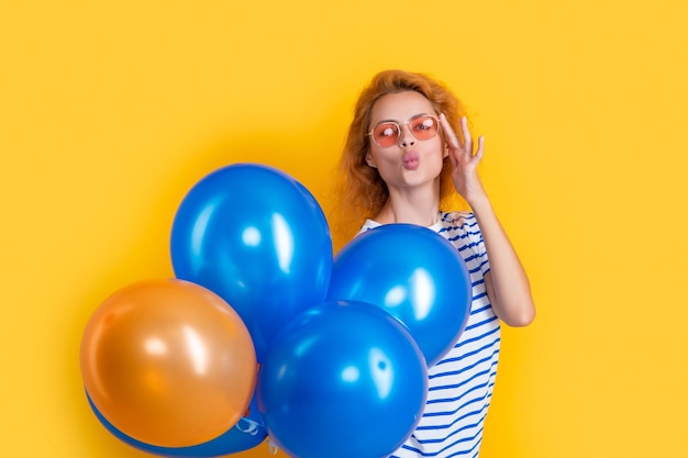 Imprezowa dziewczyna z balonem w okularach przeciwsłonecznych dziewczyna cios pocałunek trzyma balony imprezowe w studio