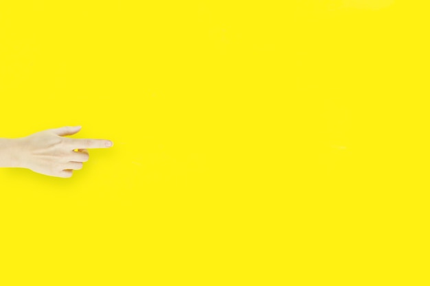 Indeks dłoni na żółtym tle, pokazujący lub wskazujący na coś niewidocznego.
