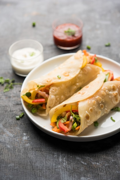 Indian Veg Chapati Wrap lub Kathi Roll, podawane w talerzu z sosem na nastrojowym tle. selektywne skupienie