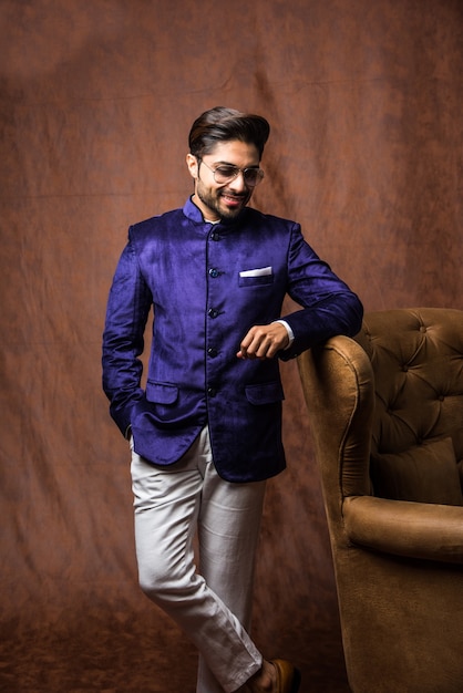 Indianin w tradycyjnym stroju LUB kurta, piżamy. Męska modelka w sherwani, pozująca lub stojąca na brązowym tle grunge, selektywne focus