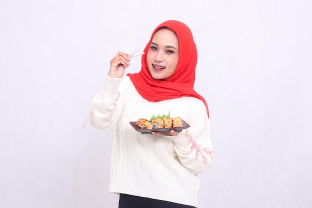 indonezyjska dziewczyna w hidżabie jest szczęśliwa, widząc przednią podnoszącą się z pałeczkami do jedzenia i niosącą