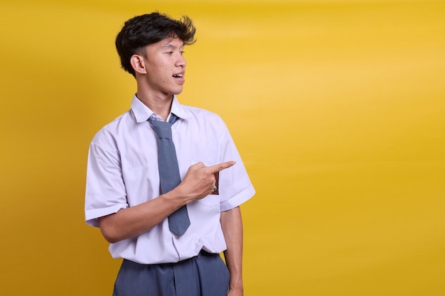 Indonezyjski uczeń szkoły średniej w mundurku z wesołym wyrazem twarzy wskazującym na bok