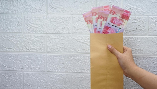 Indonezyjskie pieniądze w papierowej kopercie na białym tle białej ściany