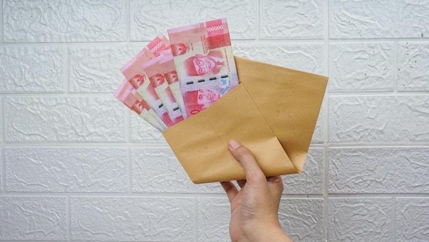 Indonezyjskie pieniądze w papierowej kopercie na białym tle białej ściany